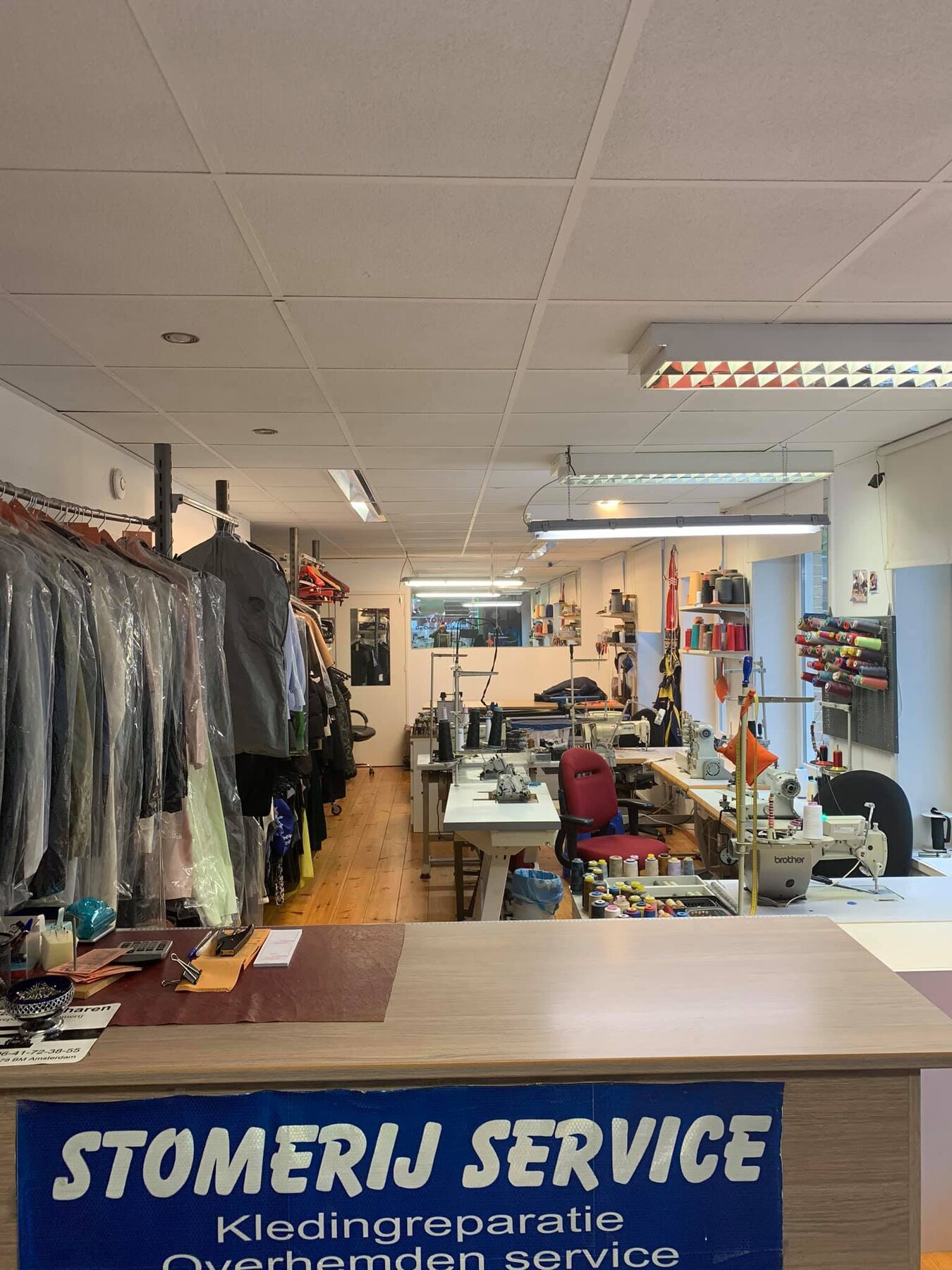 De balie van De Oranje Scharen met kleding aan het rek