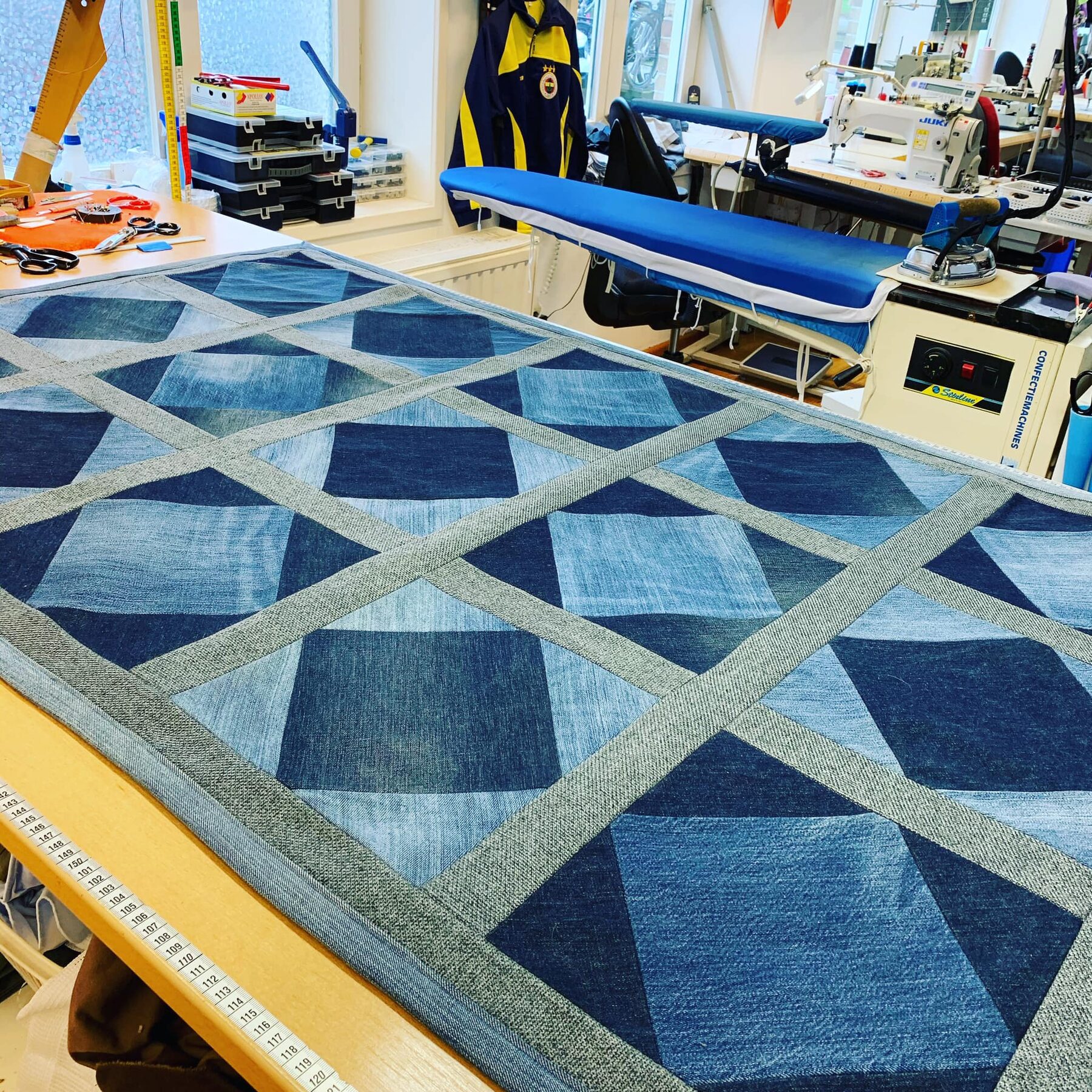 Een tapijt van denim-lappen op de werktafel in het atelier