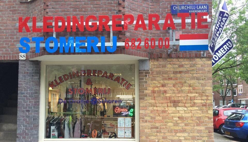 De gevel van De Oranje Scharen met de borden Kledingreparatie en Stomerij